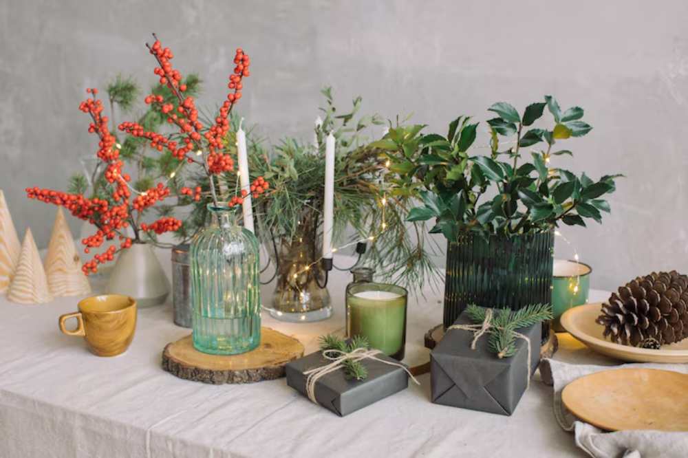A festive table setting featuring greenery, red berries, candles, wrapped gifts, and rustic decor, creating a cozy holiday atmosphere.