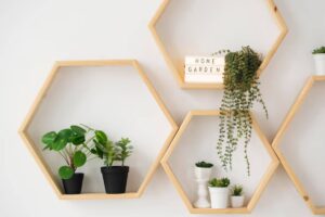 Hexagonal wooden shelves display various potted plants and a lightbox sign reading 'HOME GARDEN,' enhancing a cozy indoor atmosphere.